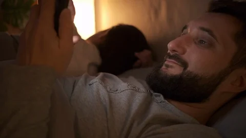 Man browsing social media using mobile phone while wife is asleep Video stock 124524378