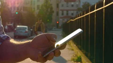 A man  is browsing some pages in the internet using a phone. Patches of sunset. Video stock 62528965