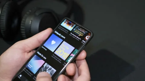 Man browsing Spotify app music catalog on a smartphone,audio streaming platform Stock Footage 145115478