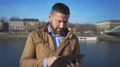 Man browsing tablet and smiling at camera on background of the river, portrait Vídeo Stock 72709891