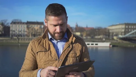 Man browsing tablet on the background of the river, portrait, sunny day  Vídeos de archivo 72709913