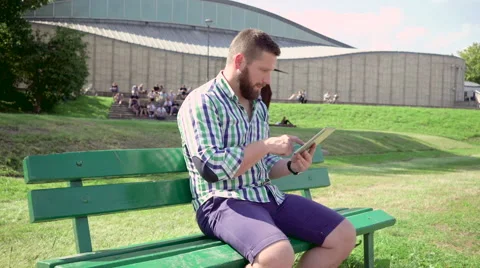 Man browsing tablet on bench. Steadicam. Vidéo 67235784