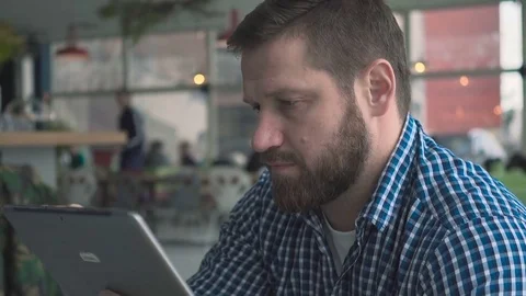Man browsing tablet computer, portrait, in cafe, close steadicam shot  库存影片 72952148