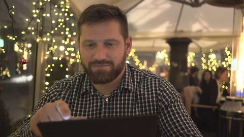 Man browsing tablet computer receiving order, cafe, night, close steadicam Vidéo 72782523