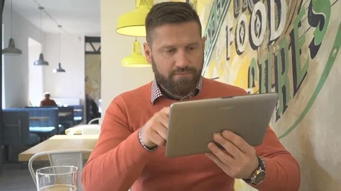 Man browsing tablet computer, smiling at camera, portrait, in cafe, steadicam Vídeos de archivo 73230371