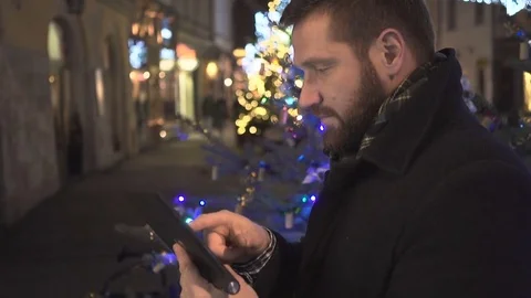 Man browsing tablet At night in city Christmas time Profile Steadicam  Vídeo Stock 72782238