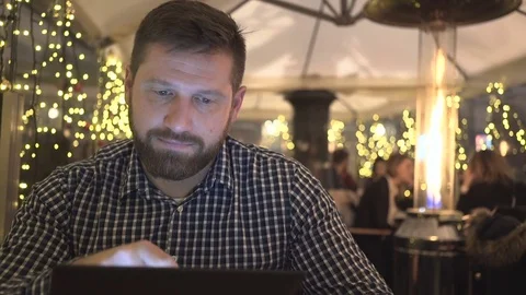 Man browsing tablet, smile at camera, cafe, night, Christmas, close steadycam  库存影片 72782571