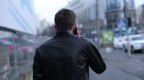 Man brunette talking on a cell going through the city Stock Footage 61430558