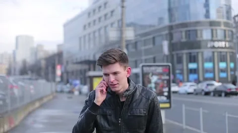 Man brunette talking on a mobile phone and laughs in the city Stock Footage 61430689