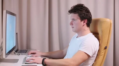 Man brunette working at a computer at home Stock Footage 60794255