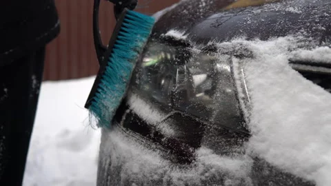 A man brushes a car headlight from snow. In winter in Russia, the car was Stock Footage 145772306