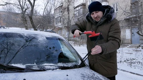 A man brushes a car windshield from snow. In winter, the car was covered with Stock Footage 149940740