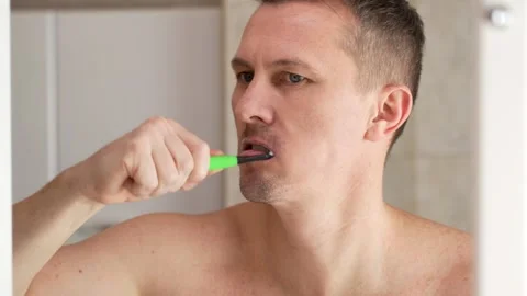 A man brushes his teeth in a bathroom Stock Footage 266818188