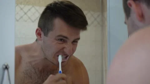 Man brushes his teeth standing in front of a mirror Stock Footage 141038810