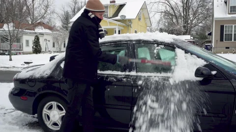 Man Brushes Snow off the Windows of a Black Car Stock Footage 147689227