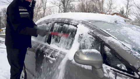 Man Brushes Snow off the Windows of a Grey Car Stock Footage 147687208
