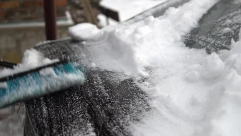 A man brushes the trunk lid of a car from snow. In winter in Russia, the car was Stock Footage 145771080