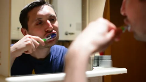 Man is brushing his teeth in the bathroom. Stock Footage 90785832