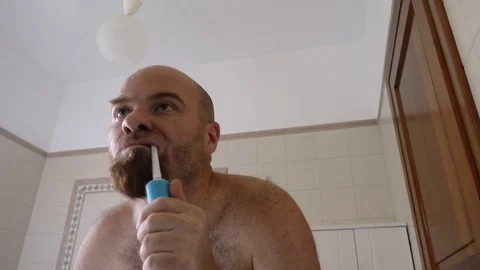 Man Brushing His Teeth with electric toothbrush in front of mirror 스톡 동영상 80125715
