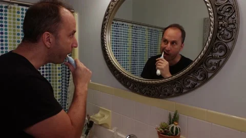 Man brushing his teeth is terrified of a creepy devil like reflection of hims Stock Footage 138744438