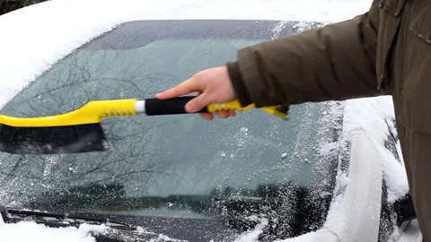 Man brushing snow ice from windscreen of car.Person cleaning fresh snow after sn Stock Footage 295878071