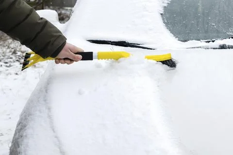 Man brushing snow from windscreen car with brush.Person cleaning fresh snow Foto stock