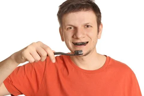 Man brushing teeth with charcoal toothpaste on white background Stock Photos