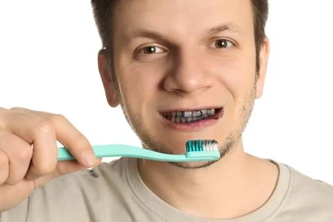 Man brushing teeth with charcoal toothpaste on white background, closeup Stock Photos