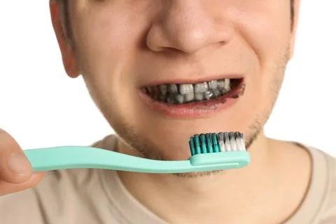 Man brushing teeth with charcoal toothpaste on white background, closeup Stock Photos