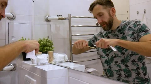 A man brushing the teeth in front of a bathroom mirror Stock Footage 325180233