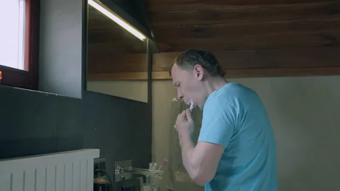 Man brushing teeth in the morning while standing in the bathroom Stock Footage 155177441