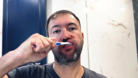 Man brushing teeth with toothbrush in a bathroom Stock Footage 253157171