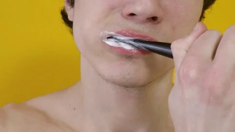 Man brushing teeth on yellow background Stock Footage 265237492