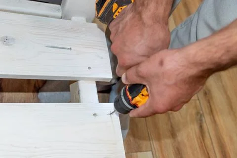 Man Builder Carpenter drilling Cordless hammer Drill Into Wooden Board bench Foto stock