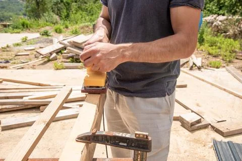 Man Builder Carpenter Sanding Surface Wooden Board Beam With Grinder machine Stockfoto's