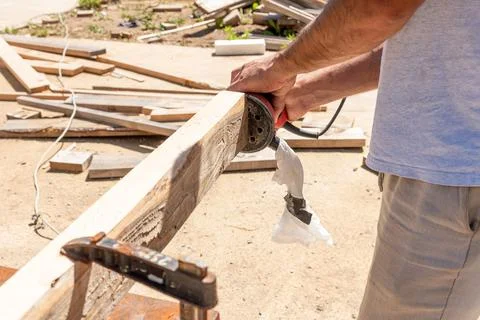 Man Builder Carpenter Sanding Surface Wooden Board Beam With Orbital Sander.. Фото