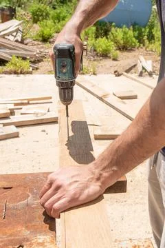 Man Builder Carpenter screw driving Cordless Drill In Wooden Board On sawhors Photos