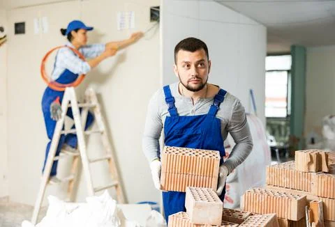 Man builder carrying bricks in construction site in apartment 写真素材