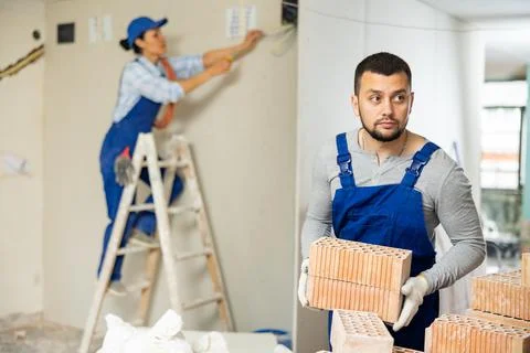 Man builder carrying bricks in construction site in apartment 写真素材