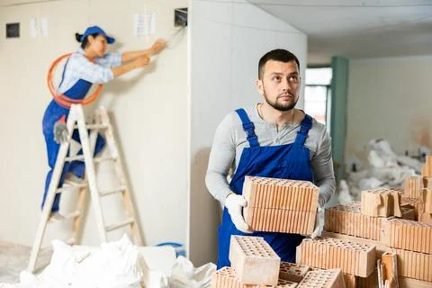 Man builder carrying bricks in construction site in apartment 写真素材
