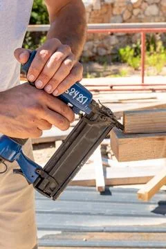 Man Builder craftsman Carpenter hammers nails on Wooden Board Beam With finis 库存照片