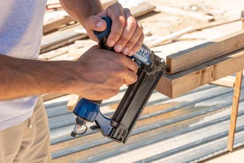 Man Builder craftsman Carpenter hammers nails on Wooden Board Beam With finis 스톡 사진
