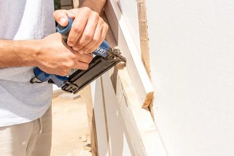 Man Builder craftsman Carpenter hammers nails on Wooden Board Beam With finis Photos
