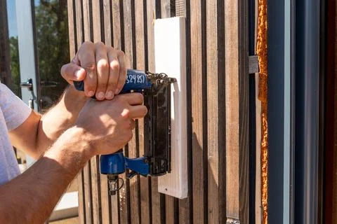 Man Builder craftsman Carpenter hammers nails on Wooden Board Beam With finis 스톡 사진