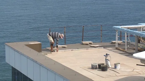 A man builder does the floor on the roof of the hotel, on the beach. Stock Footage 95626551