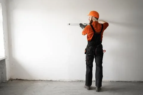 Man builder in hardhat drilling wall with drill perforator. construction or.. Stock Photos