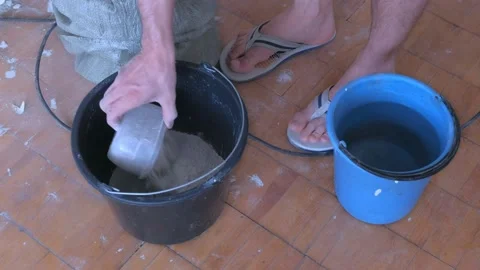Man builder mixing dry kneads putty plaster with water in bucket, closeup view. Stock Footage 146164296