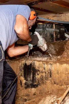 Man builder repairman drill perforator hole in concrete in basement wooden .. Stock Photos
