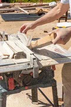 Man builder saws and grinds wooden boards, carpenter craft works with power e 库存照片