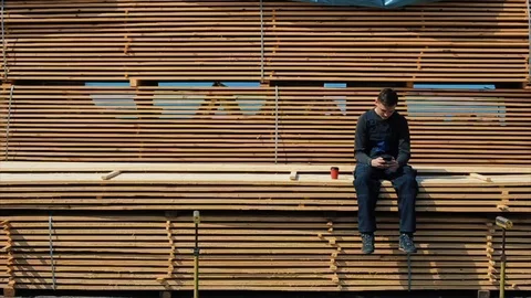 The man builder wearing uniform sits on the long planks. 库存影片 112177063
